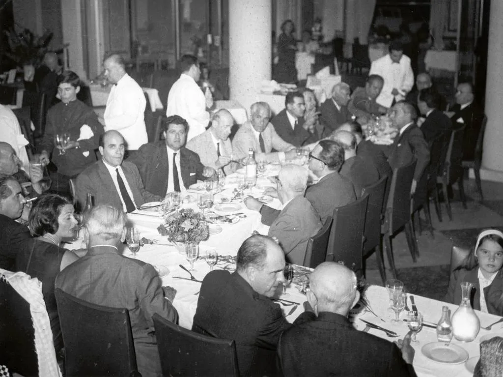 Συνεστίαση στο κέντρο «Καλαμάρα» της πλατείας Πολυγύρου. Διακρίνονται ο Ανδρέας Παπανδρέου, η μικρή του κόρη, ο Νικόλαος Τερζόγλου, ο Αλέξανδρος Μπαλτατζής, ο Άγγελος Αγγελούσης, ο Λάκης Λασκαρίδης, ο Βασίλειος Ιντζές, ο Ιωάννης Κυριαφίνης και πολλοί άλλοι